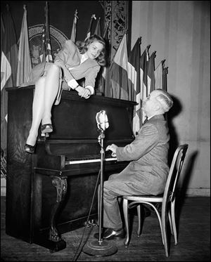 In this Feb. 10, 1945 file photo, Vice President Harry S. Truman plays the piano as actress Lauren Bacall lies on top of it during her appearance at the National Press Club canteen in Washington. 
