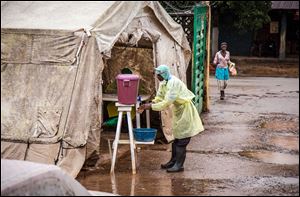 A health worker cleans his hands with chlorinated water before entering a Ebola screening tent, at the Kenema Government Hospital, about 186 miles from the capital city of Freetown in Kenema, Sierra Leone.