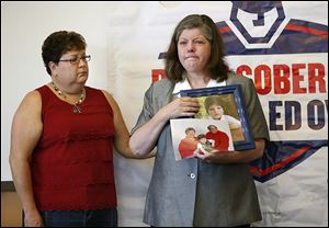 Shelen Stevens of Weston, Ohio, holds photos of her deceased parents, Bill and Sharon DeWitt, and her son at a news conference on Tuesday at the Ohio Highway Patrol post in Bowling Green. At left is Sandy Wiechman, BGSU safe communities coordinator.