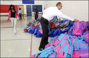 Jason Bartschy, right, on the The Salvation Army Board of Directors, gets backpacks to hand out during The Salvation Army’s Annual “Tools for Schools” Distribution at The Salvation Army on August 13, 2014. Huntington Bank has donated more than 1,800 backpacks to give to local families in need, with The Anderson’s and the community donating additional supplies. Volunteers Jerrae McGee, center, and  Marcus Veley, back left, help hand-out backpacks during the event.