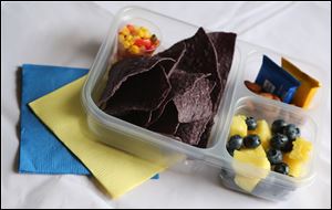 A lunch sporting the colors of a favorite team would appeal to a young fan. Here is one in University of Michigan colors: Corn salsa and blue corn chips, roasted almonds, blueberries, and pineapple chunks.