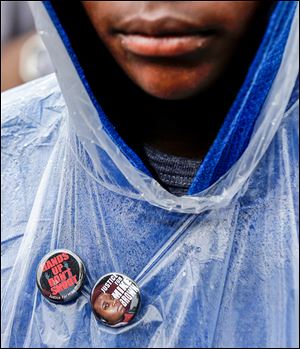 A man wears buttons of support as he visits the site where Michael Brown was shot and killed. 