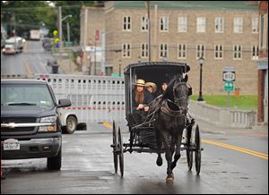 An Amish family rides along Route 812 in Heuvelton, N.Y., near the command center at the Heuvelton Volunteer Fire Department, Friday. The investigation continues into the abduction and return of two young Amish sisters who were selling vegetables at their family’s roadside stand.