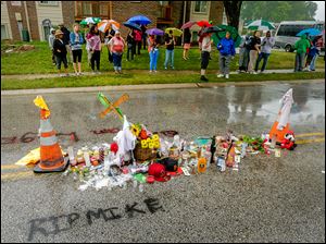 People gather at a makeshift memorial for Michael Brown on Saturday at the site where Mr. Brown was shot by police a week ago in Ferguson, Mo. 