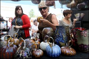 Ashley Hampton, of Perrysburg, left, Karen Crawford, of Temperance, center, and Janna Lazelle-Lake, of West Toledo, right, browse through a booth featuring glass pumpkins.