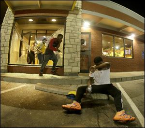 People leave a McDonald's restaurant after taking refuge from tear gas Sunday in Ferguson, Mo.
