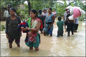 Nepalese villagers carry their belongings while wading through a flooded street to move to safer ground, at Bardia, in western Nepal Friday.