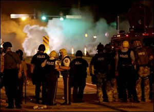 Police wait to advance after tear gas was used to disperse a crowd Sunday during a protest for Michael Brown, who was killed by a police officer last Saturday in Ferguson, Mo.