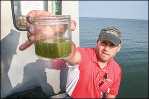 Wildlife biologist Tory Gabriel, Ohio Sea Grant fisheries outreach coordinator, holds a jar of microcystis algae pulled from Lake Erie.