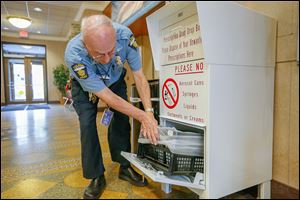Toledo police officer Robert D’Agostino checks the drug drop-off box in the foyer of the Safety Building downtown on Erie Street. 