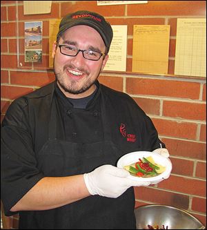 Chef Wes Wright of Revolution Grille holds one of his Pansoti, or handmade ravioli stuffed with grilled chicken, spinach, and ricotta cheese during the pre-party.
