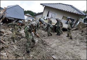 Japan Ground Self Defense Force personnel search for missing residents in a mud-ridden residential area following a massive landslide in Hiroshima. 