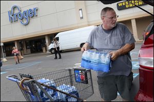 Jeff Rhoades of West Toledo loads bottled water into his car at the Kroger store on Monroe Street and Secor Road. Fears that Toledo drinking water is again unsafe were spreading Thursday leading many to stock up.