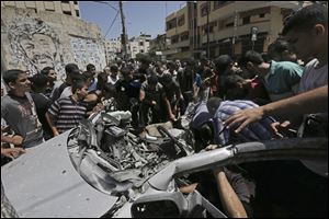 Palestinians inspect the wreckage of a vehicle following an Israeli airstrike at the main street in Gaza City in the northern Gaza Strip, Thursday.