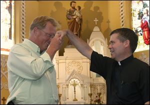 St. Joseph Maumee parish representative John Hoover, left, and Father Keith Stripe demonstrate the Mano Pa, a Philippine blessing.