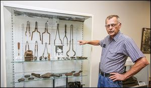 Paul Coffman, presidente de la Collectors Club Tiffin Glass, muestra diferentes herramientas de fabricación de vidrio en la nueva sala de archivo.
