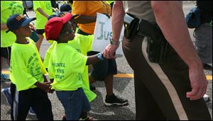 St. Louis County Police Sgt. Colby Dolly joins hands with five-year-old Zion King Frenchie during a march.
