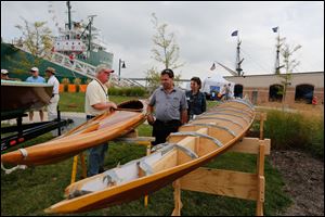 Mark Sturdevant of Toledo, left, shows a finished 18-foot kayak that he built primarily of cedar to Brad Stough and Cecelia Claus, both of Deerfield, Mich.