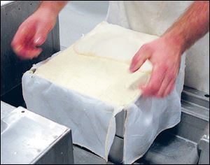 Cheese is pressed into a mold to remove liquid at Henningâs cheese factory.