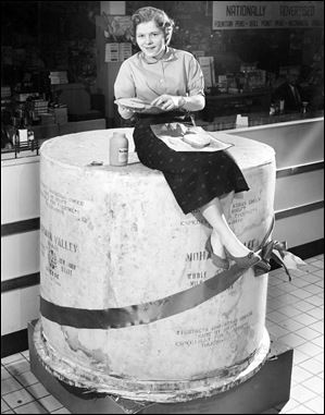 Preparing a cheese sandwich atop Tiedtke's annual Christmas 2-ton cheese is Evelyn Durdel in this 1955 file photo. The cheese was 5 feet high and 4 and a half feet in diameter.