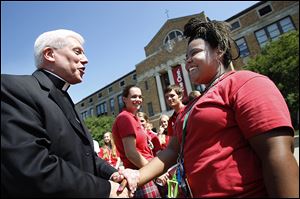 Bishop Thomas, 55, greets Central Catholic High School senior A’yanna Bishop outside the school on Cherry Street. She was shooting yearbook pictures.