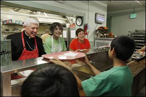 Bishop Daniel E. Thomas serves at Helping Hands of St. Louis Outreach Center in East Toledo with Jean Scott of Tontogany, Ohio, center, and Helen Bare, of Perrysburg, both of Saint John XXIII Catholic Parish in Perrysburg.