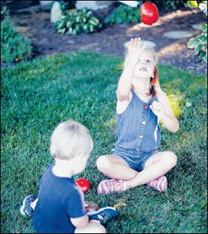 Elly and her baby brother, Jacob, play with vegetables in the yard.