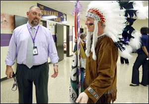 Waite High School principal Todd Deem greets senior Jason Kendall, who is dressed as the school’s Indian mascot, while young Kendall helps out with the freshman orientation Tuesday.