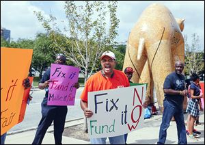 Alexis Bob, a member of Amalgamated Transit Union Local 689, leads a chant outside One Government Center.