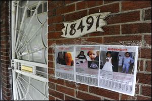 In this June 10, 2014, file photo, flyers of a missing woman and children are taped to the brick home of Alicia Fox in Detroit.  