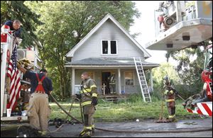 Firefighters clean up the site of a vacant house fire at 857 Tecumseh Street in Toledo.