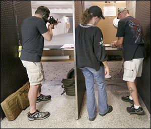 Army infantryman Geoff Earnhart of Perrysburg aims his AR15 Smith & Wesson M&P 15 at Shooters of Maumee. At right are Kelly and Brian Smith of Toledo.