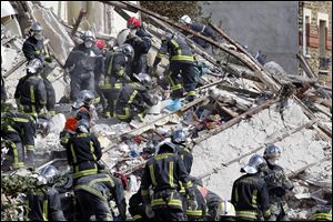 French firemen search in the rubble of  a building after an explosion collapsed it Sunday in Rosny-sous-Bois, outside Paris.