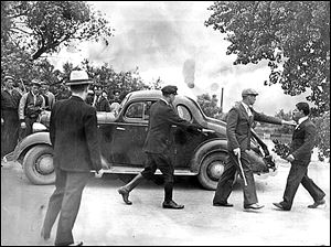 A group of vigilantes stop a car on the road to Monroe, Mich., while another one halts the vehicle's owner.  Every automobile attempting to enter Monroe  June 11, 1937, was stopped by armed vigilantes who are trying to keep sympathizers of the Newton Steel Co. strike from entering Monroe. 