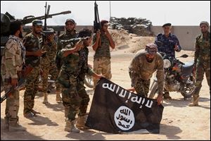 Iraqi security forces hold a flag of the Islamic State group they captured during an operation outside Amirli, some 105 miles north of Baghdad, Iraq, Monday, Sept. 1, 2014.