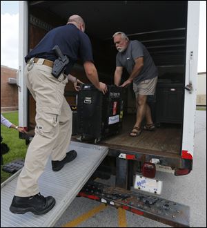 Oregon, Ohio Det. Ryan Spangler, left, helps Tony Aringer load band instruments into a moving van at the Oregon police station