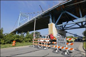 Construction workers work underneath the Anthony Wayne Bridge, closing Miami Street,  Wednesday, September 3, 2014. 