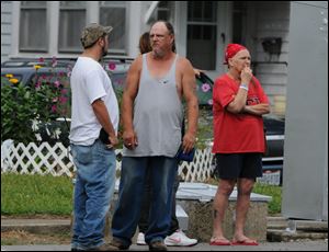Residents look on as police investigate a home in Bucyrus, Ohio, where one of four men were found beaten to death Monday. 