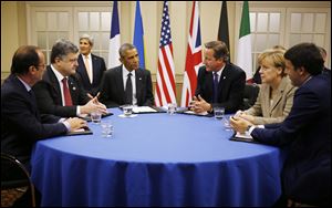 President Obama, fourth from left, is seated at a table with, from left to right: France's President Francois Hollande; Ukraine President Petro Poroshenko; British Prime Minister David Cameron; German Chancellor Angela Merkel; and Italian Prime Minister Matteo Renzi as they meet about Ukraine at the NATO summit at Celtic Manor in Newport, Wales, today. U.S. Secretary of State John Kerry is seated at rear left. 