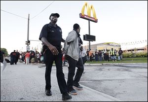 A protester is removed by police from blocking traffic near a McDonald’s restaurant on Mack Avenue in Detroit. 