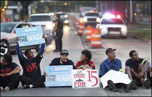 Protesters sit in Mack Avenue outside a McDonald’s restaurant in Detroit during a rally urging workers be paid $15 an hour.