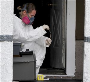 Brenda McNeely collects evidence at a home in Bucyrus Tuesday, where one of four men were found beaten to death.
