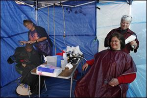Volunteers Jenny King, of Toledo, second from left, and Jan Archambeau, of Whitehouse, cutting hair at Tent City. Getting haircuts are Zidarion Wooden, 5, left, and Mary Siders, both of Toledo.  