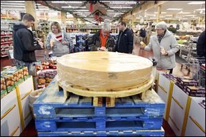 Shoppers gather around what remains of the giant cheese wheel Sunday at The Andersons. Portions also were distributed to The Andersons Maumee and Sylvania stores.