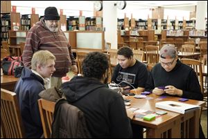 Rob Ellis, standing, visits with, from left,  Randall Ciski, 17, Paul Ellis, 17, David Ellis, 14, and Elijah Lawrence, 19, at the Main Library downtown. Mr. Ellis says it’s a sad fact that libraries and schools are no longer places in which you can feel totally safe. 