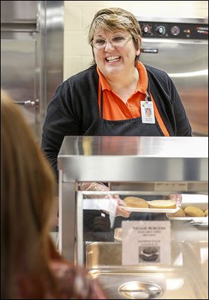 Assistant head cook Jackie Jurski serves lunch with a smile at Perrysburg High School. Administrators encourage staff to come up with new ideas, then they support the projects.