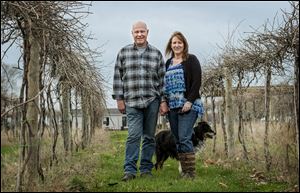 Doug and Laura Rufenacht with their dog Bingo stand near their Marquette grape vines at Majestic Oak Winery. The winery offers four whites, three reds, and two fruit wines. Last year it produced more than 3,000 gallons of wine.