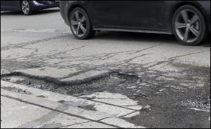 Potholes, such as this one in Detroit, are not an uncommon sight on Michigan’s roadways.