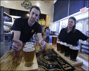Koby Harris, brewery production manager, left, and Sandra Cain, assistant director of retail operations, present their freshly brewed beers at Innovation Brew Works in March.