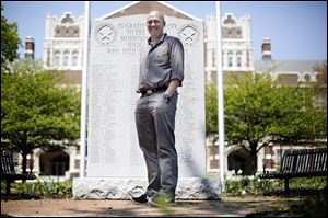 Waite High School teacher Joe Boyle,  in front of the memorial dedicated to students who died in World War II.